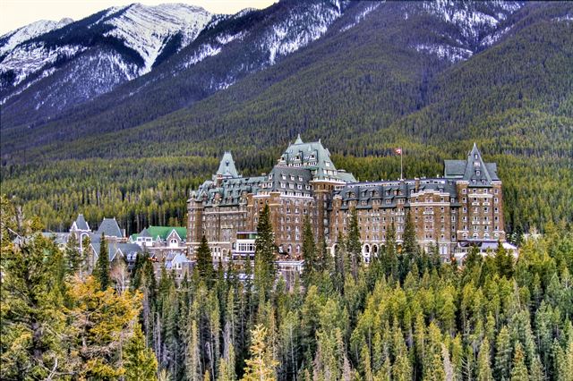 Fairmont Banff Springs hotel among pine forest below snow-dusted peaks in Banff National Park