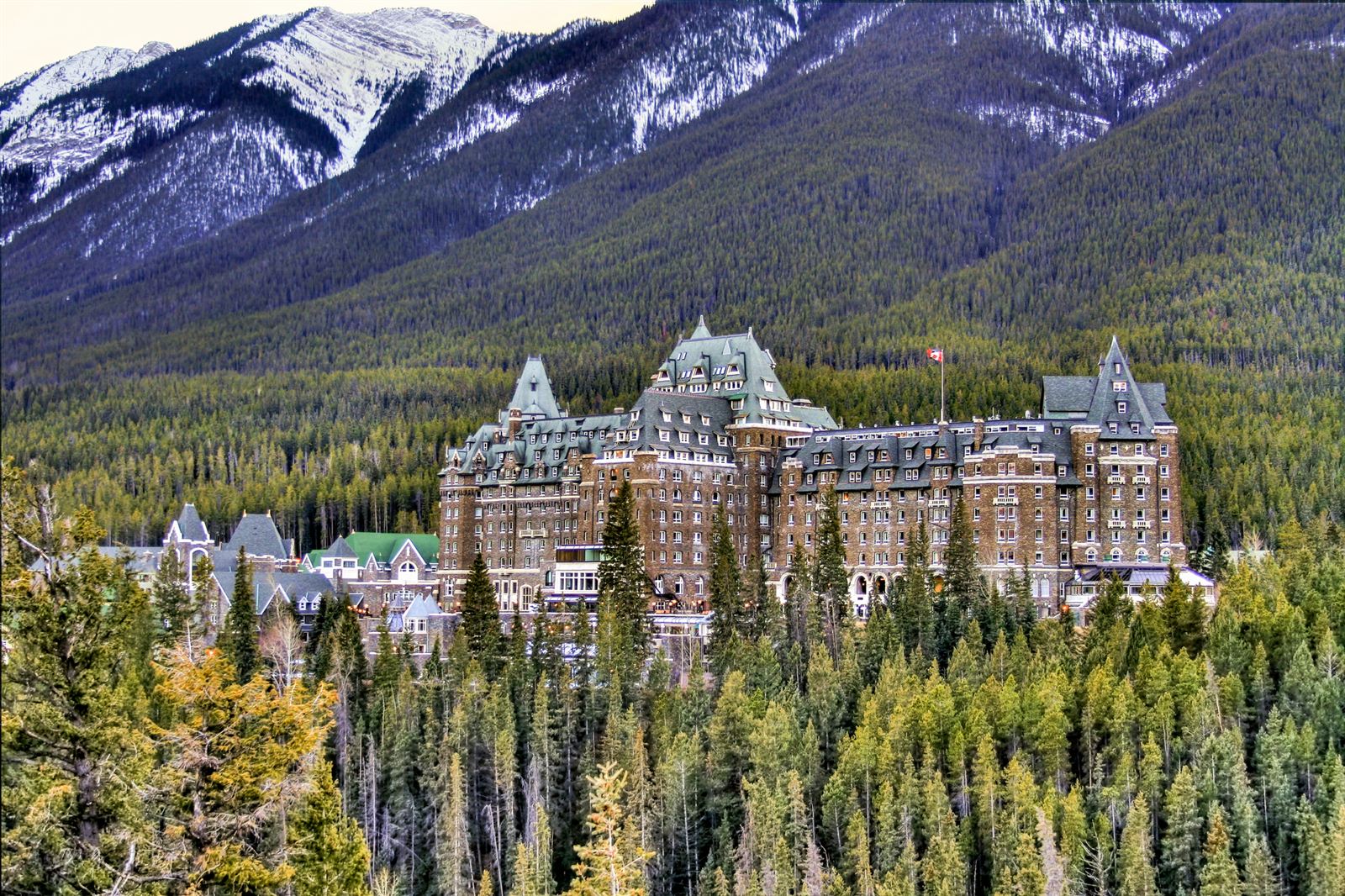 Fairmont Banff Springs hotel among pine forest below snow-dusted peaks in Banff National Park