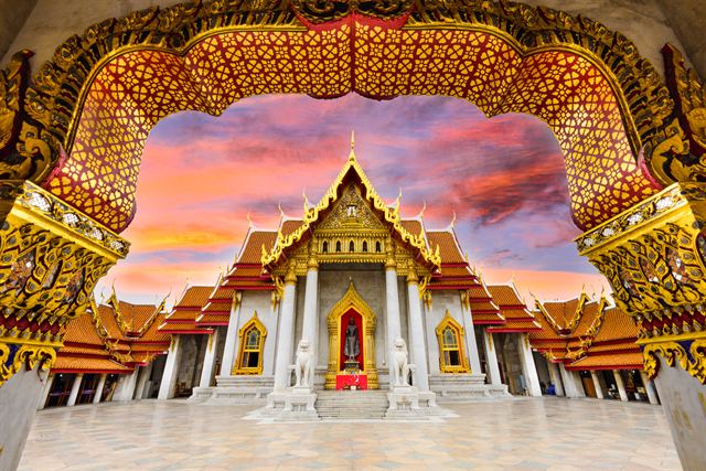 The Marble Temple (Wat Benchamabophit) framed by an ornate gateway at sunset