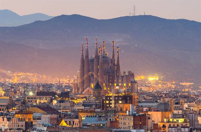 Sagrada Familia rising above Barcelona rooftops at dusk with the Collserola hills behind