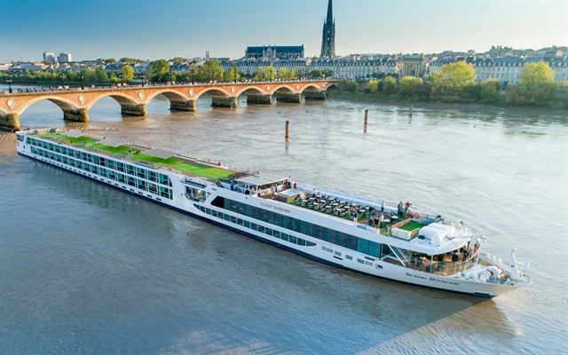 River cruise ship on the Garonne by the stone Pont de Pierre and the Bordeaux skyline