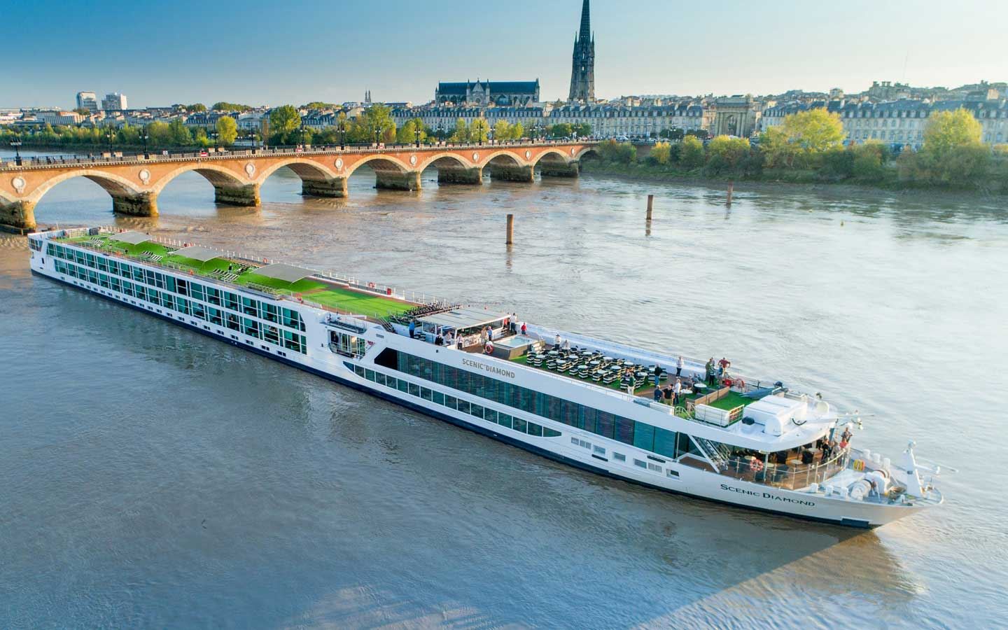 River cruise ship on the Garonne by the stone Pont de Pierre and the Bordeaux skyline