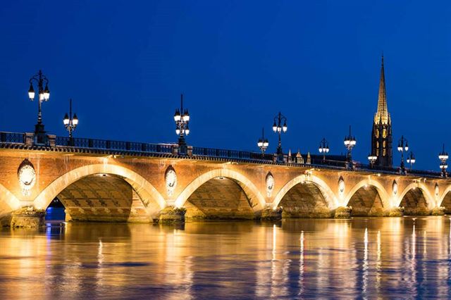 Arches and lamps of the Pont de Pierre lit at night over the Garonne in Bordeaux