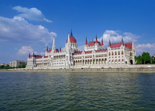 Hungarian Parliament Building with red roofs and spires on the Danube under blue sky