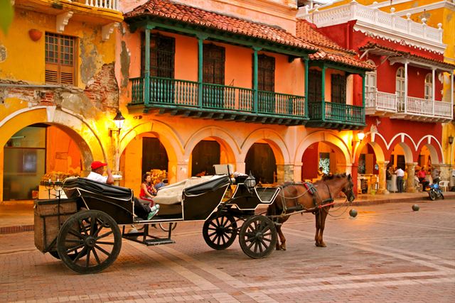 Horse-drawn carriage beneath colorful colonial balconies on Plaza de los Coches, Cartagena, Colombia