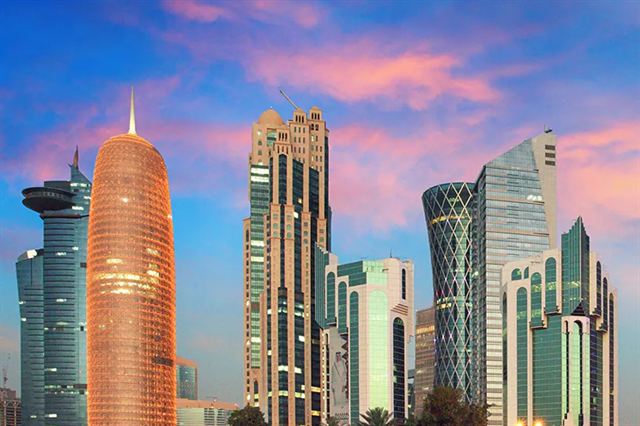 Doha West Bay skyscrapers including the cylindrical Burj Qatar tower at sunset