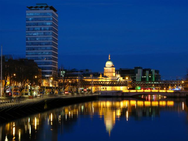 Ha'penny Bridge over the River Liffey in Dublin lit up at night with reflections