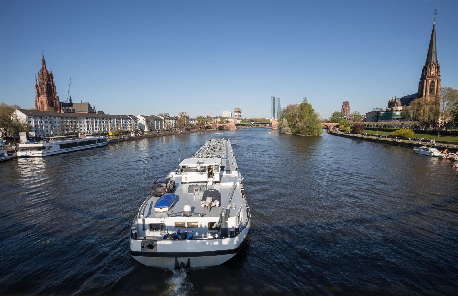 Barge on the Main river in Frankfurt with the cathedral spire and riverside buildings
