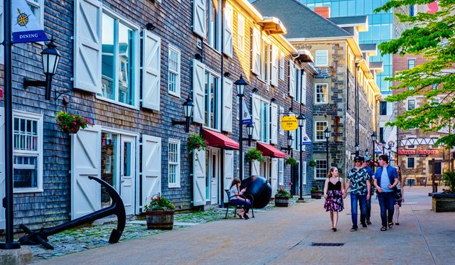 Visitors strolling past restored wooden warehouses at Historic Properties on the Halifax waterfront, Nova Scotia