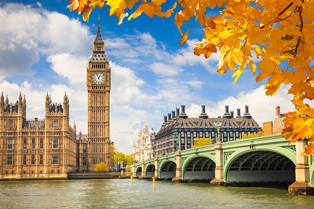 Big Ben and Westminster Bridge framed by autumn leaves