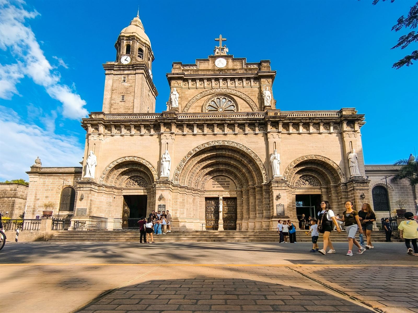 Manila Cathedral's Romanesque Revival facade and bell tower in Intramuros under bright blue sky