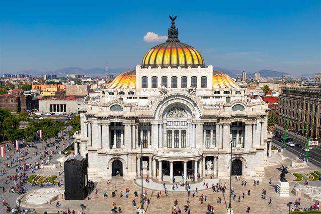 White marble Palacio de Bellas Artes with its golden domes above a busy plaza in Mexico City
