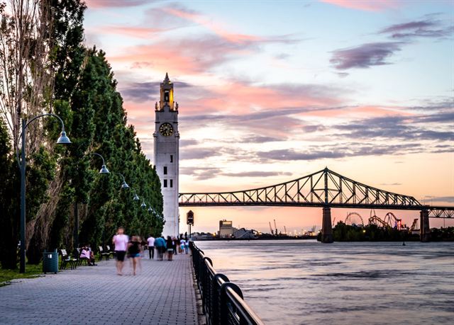Old Port promenade in Montreal with the Clock Tower and Jacques Cartier Bridge over the St. Lawrence at sunset