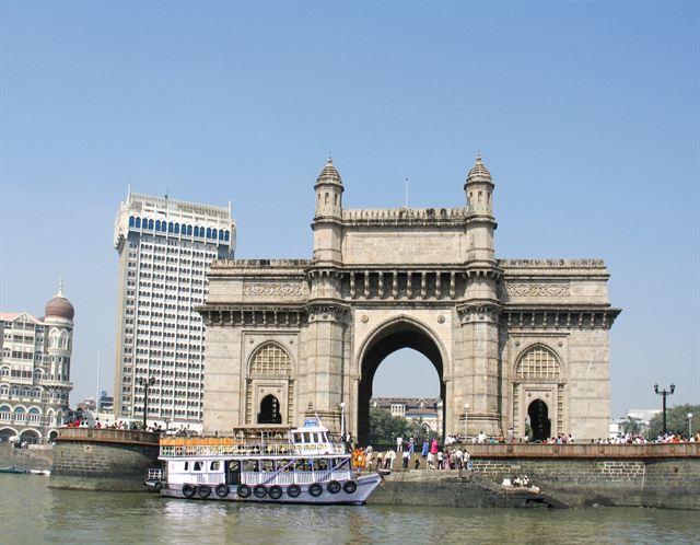 Gateway of India arch on the Mumbai waterfront with tour boats and the Taj hotel tower