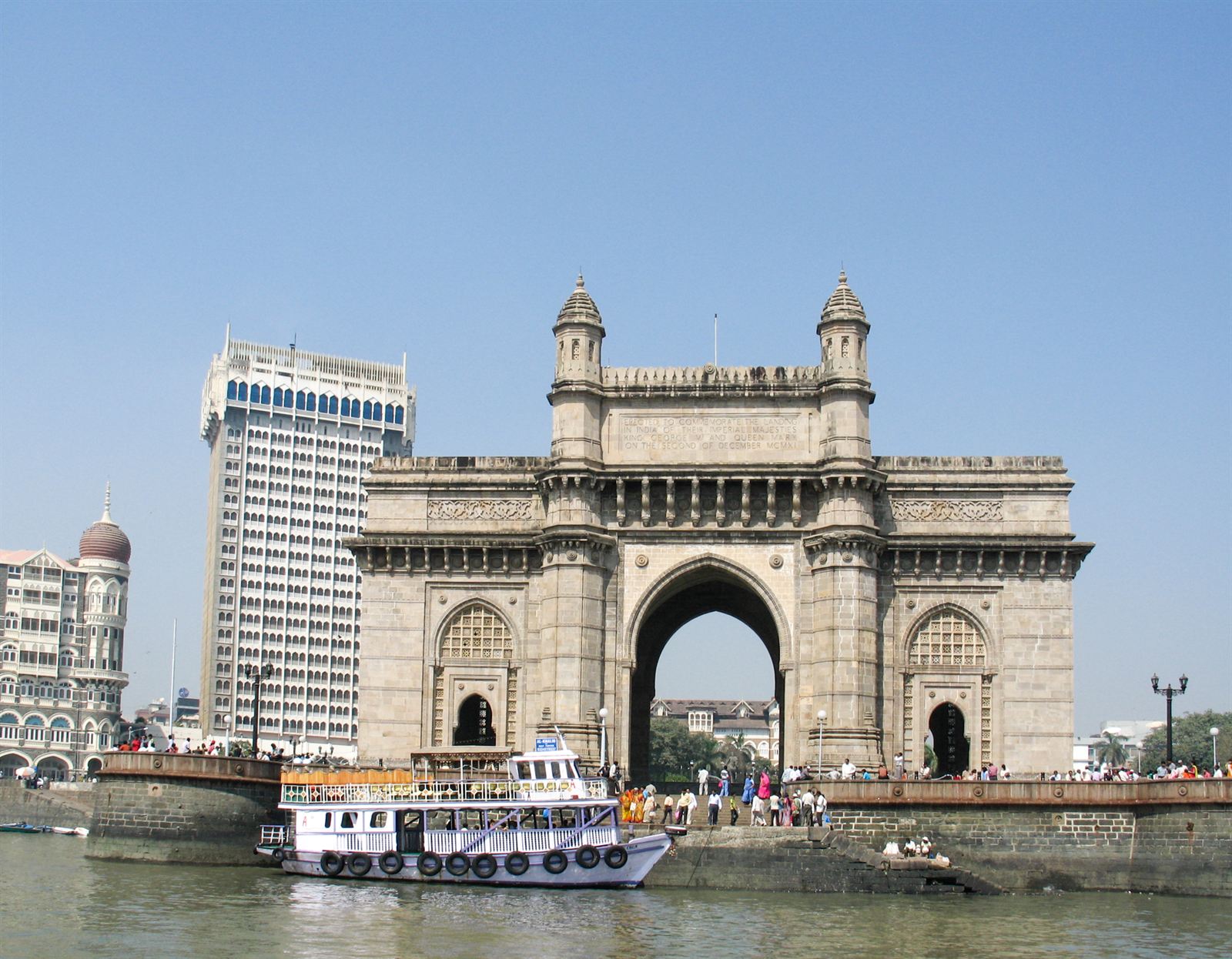 Gateway of India arch on the Mumbai waterfront with tour boats and the Taj hotel tower