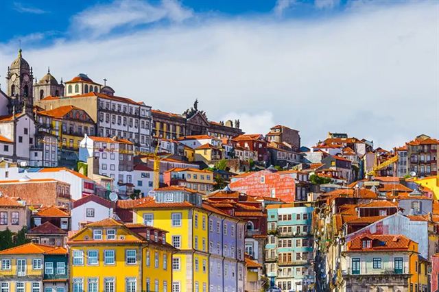 Colorful tiled houses stacked on the hillside of Porto's old town under blue sky