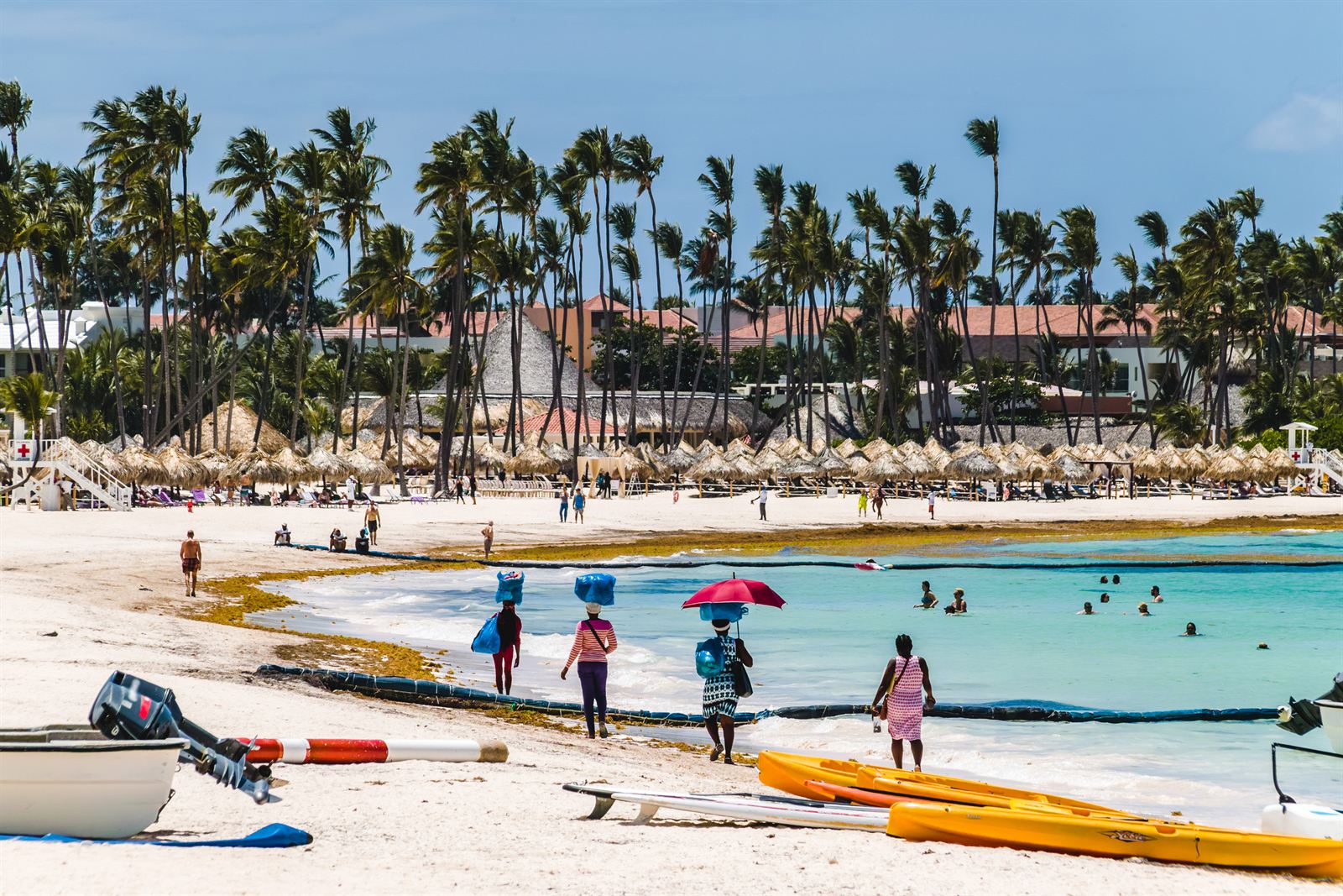 Palm-lined Bávaro beach with beach umbrellas, boats and swimmers in Punta Cana, Dominican Republic