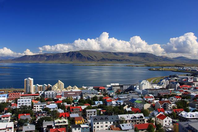 Colorful rooftops of Reykjavík with the harbor and Mount Esja across the bay
