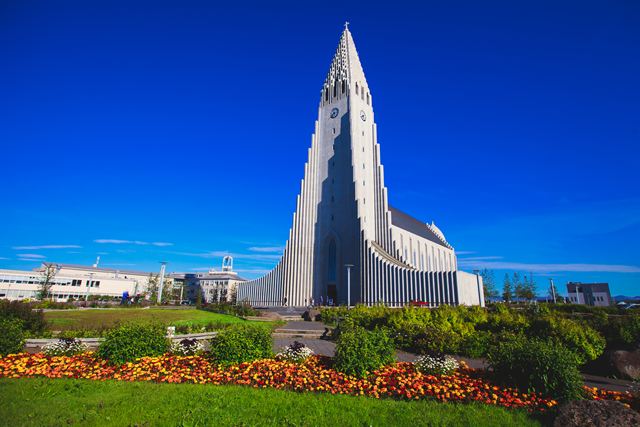 Hallgrímskirkja church towering over a flower-filled park in Reykjavík on a sunny day