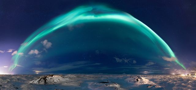 Northern lights arching across the night sky over Reykjavík and the Reykjanes peninsula