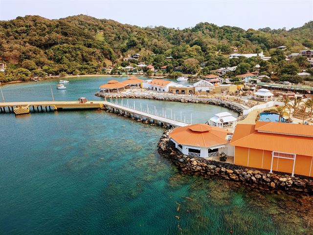 Aerial view of the cruise dock, orange-roofed terminal buildings and green hills at Coxen Hole, Roatan
