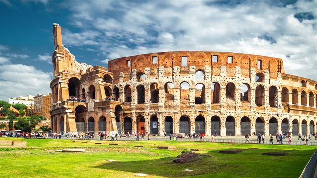 The Colosseum on a sunny day with a green lawn in front