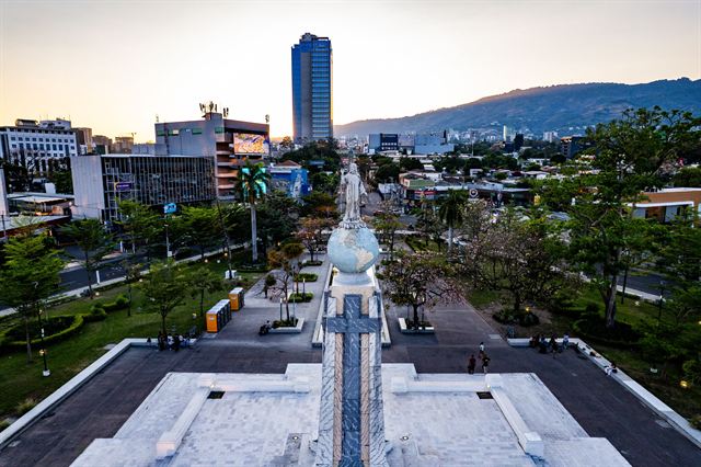 Monumento al Divino Salvador del Mundo on its plaza in San Salvador with a tower and mountains at sunset
