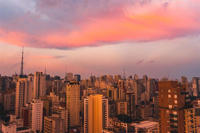 Dense Sao Paulo skyline and Paulista radio towers glowing under pink and orange sunset clouds