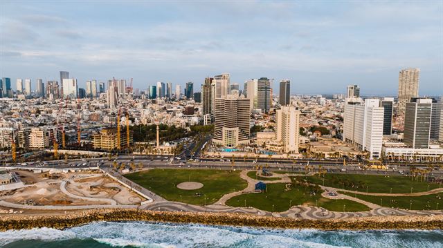 Old Jaffa port with fishing boats and stone houses, and the Tel Aviv skyline beyond, Israel
