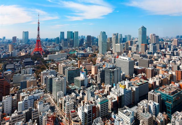 Tokyo skyline under a blue sky with the red-and-white Tokyo Tower among high-rises