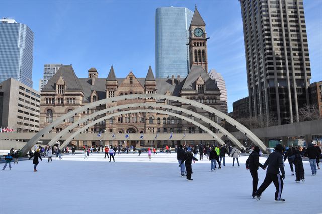 Skaters on the Nathan Phillips Square rink below the arches and Old City Hall clock tower, Toronto