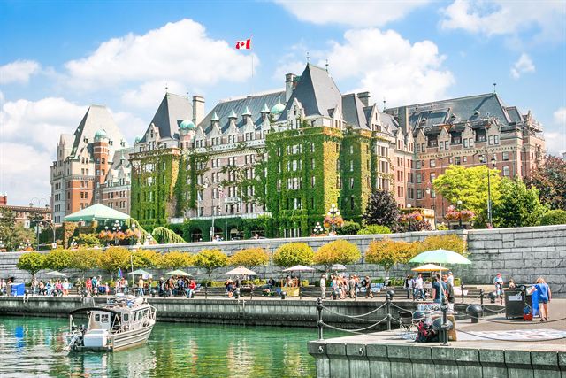 Ivy-covered Fairmont Empress hotel above the Inner Harbour walkway and boats in Victoria, British Columbia